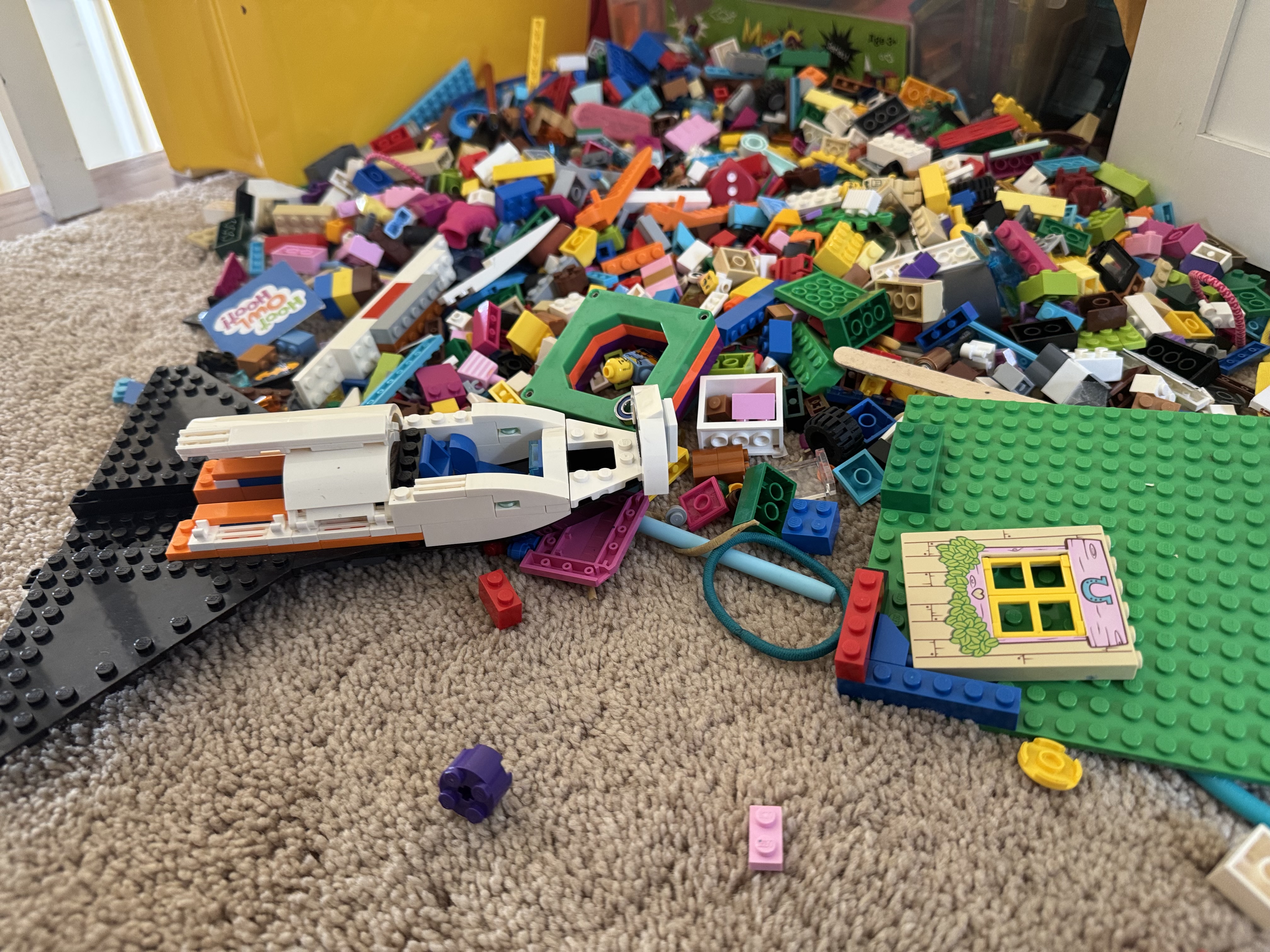 A mountain of loose Lego bricks with a partially built spaceship and house in the foreground